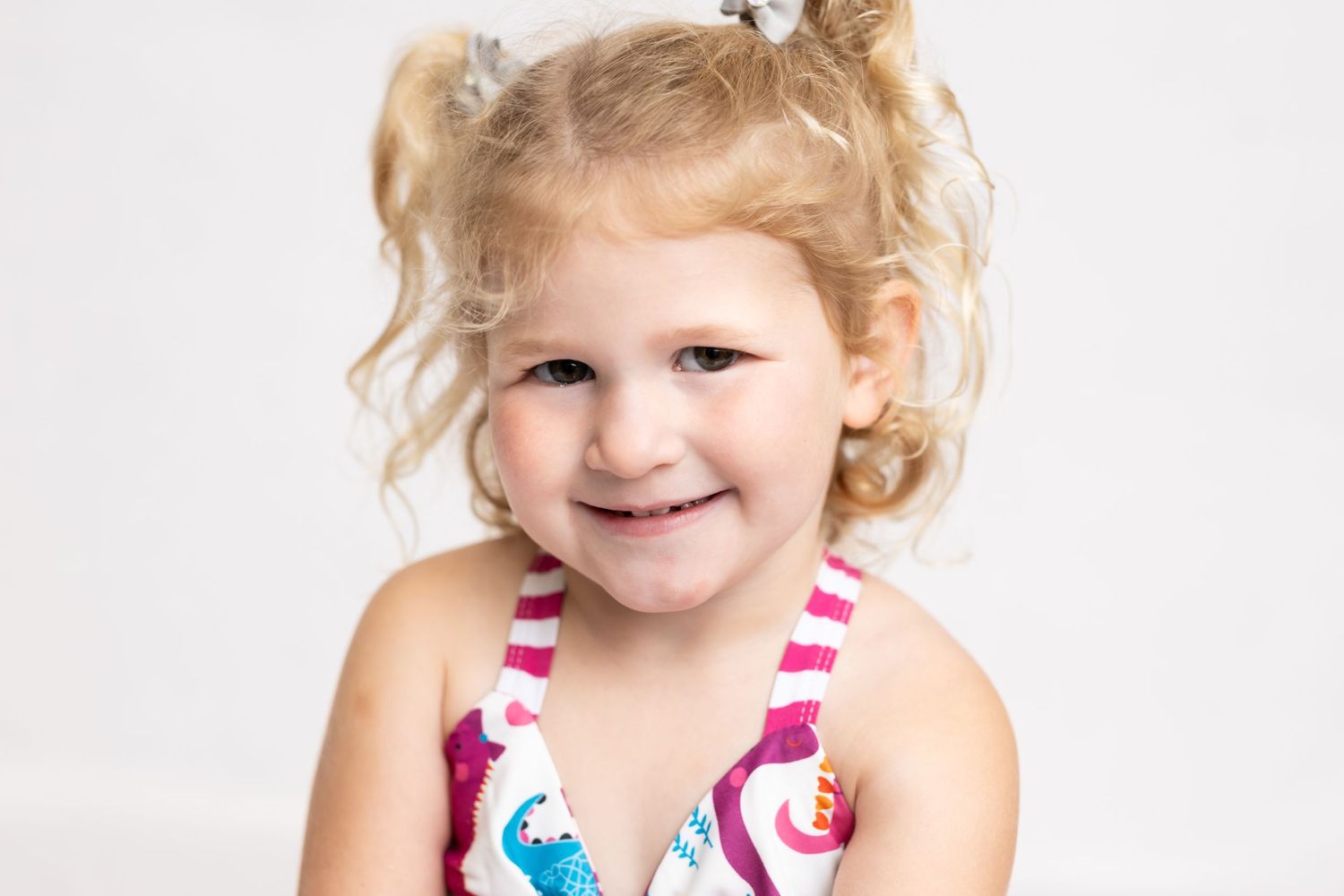 Close-up studio portrait of a smiling child in summer attire.