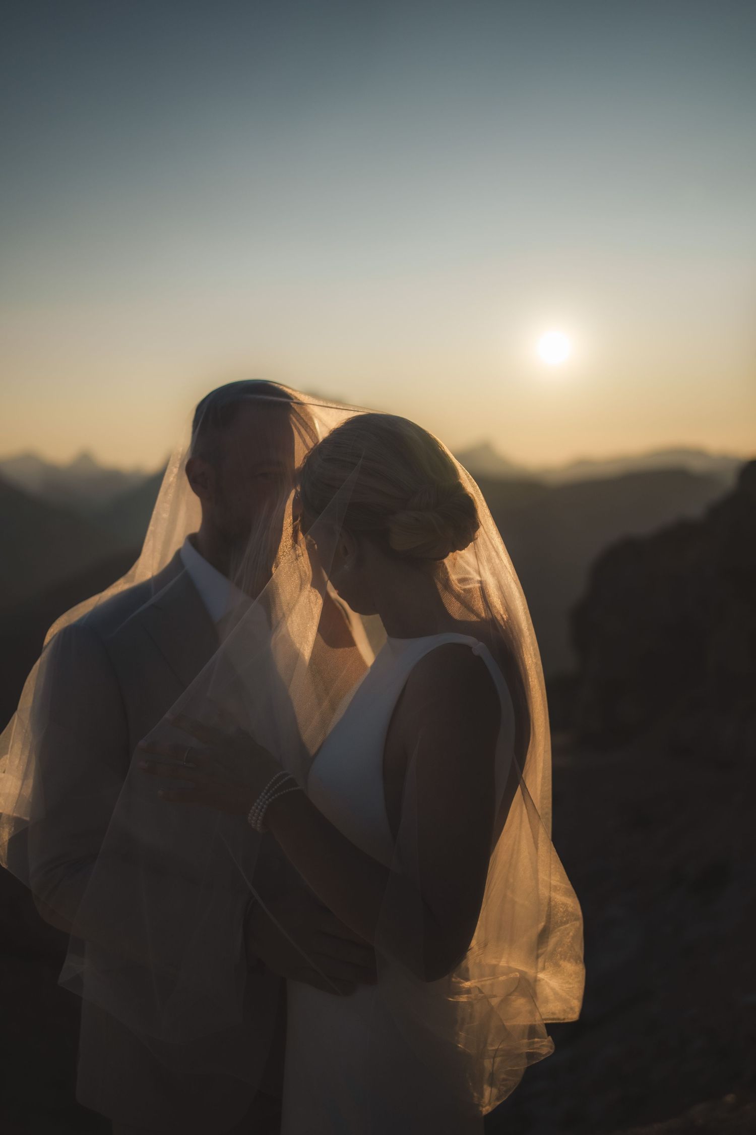 Cinematic elopement photographer capturing a couple hugging on a dramatic mountain peak in the Dolomites.