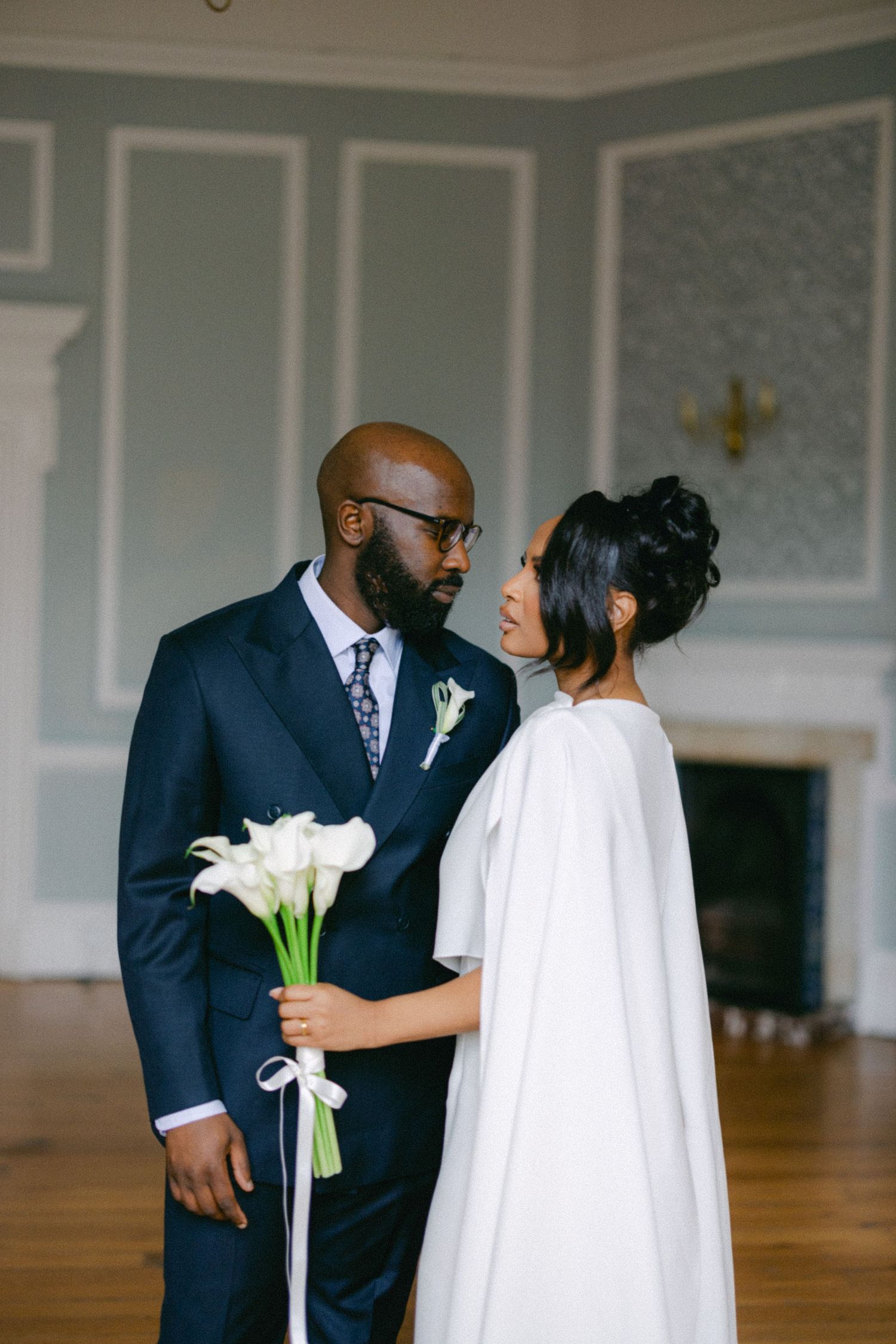 A tender wedding moment captured with elegant white calla lilies and sophisticated formal attire.