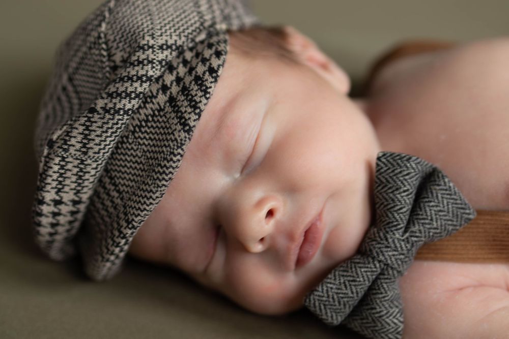A person in a houndstooth patterned jacket rests their head against a wooden surface.