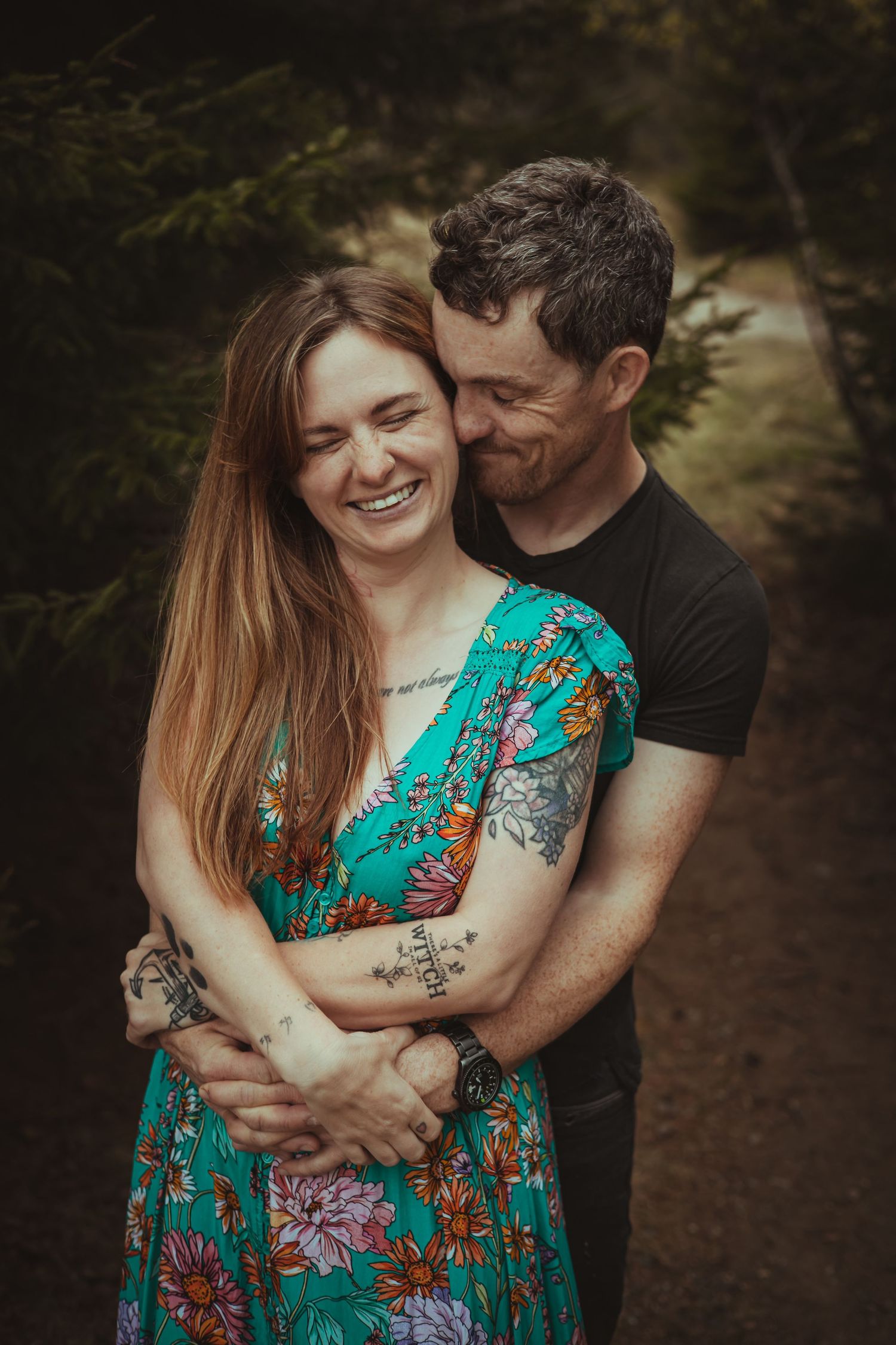 Romantic outdoor couple photos showing embrace in turquoise floral dress among trees.