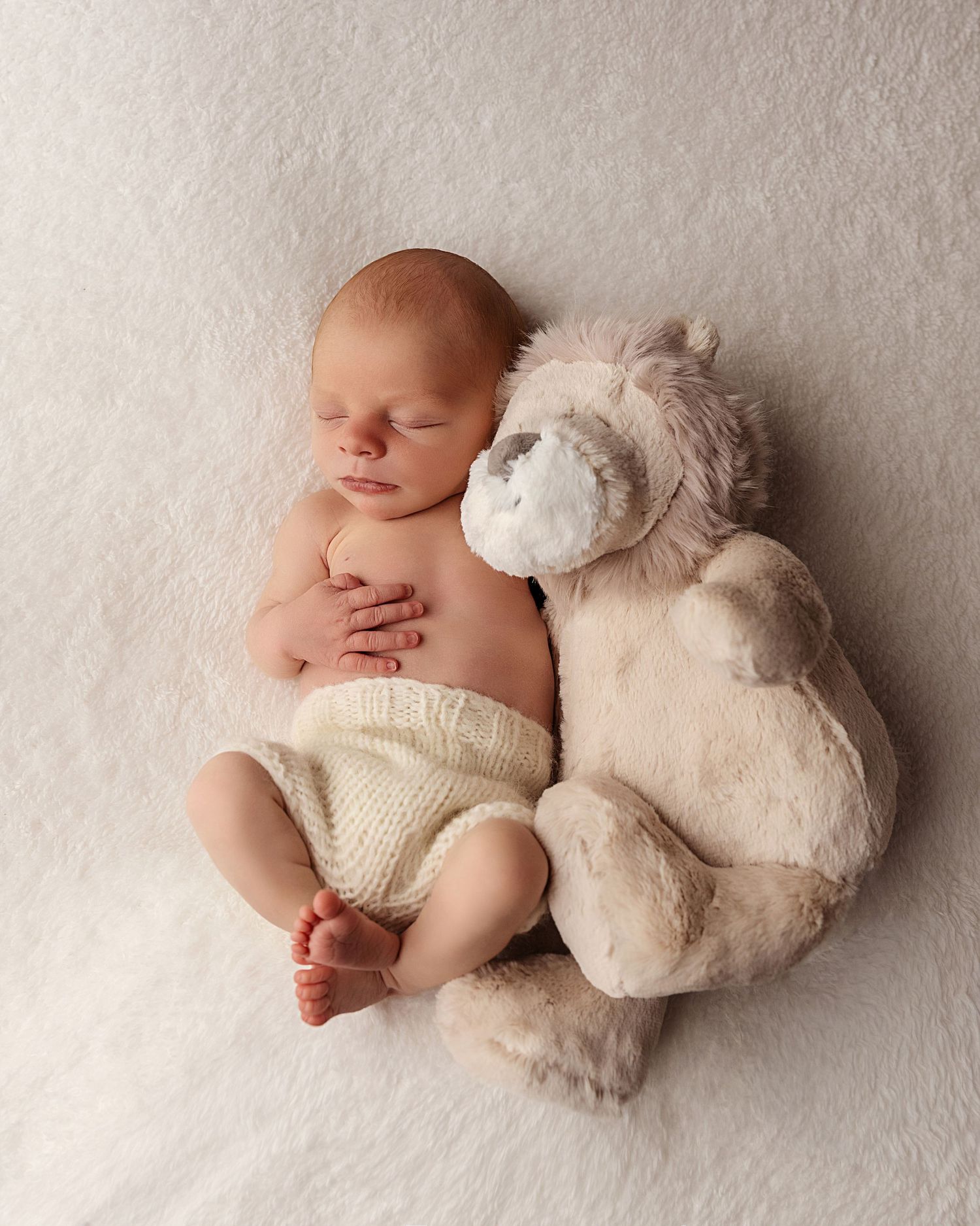 image of Baby boy on a fluffy white background snuggling his teddy bear