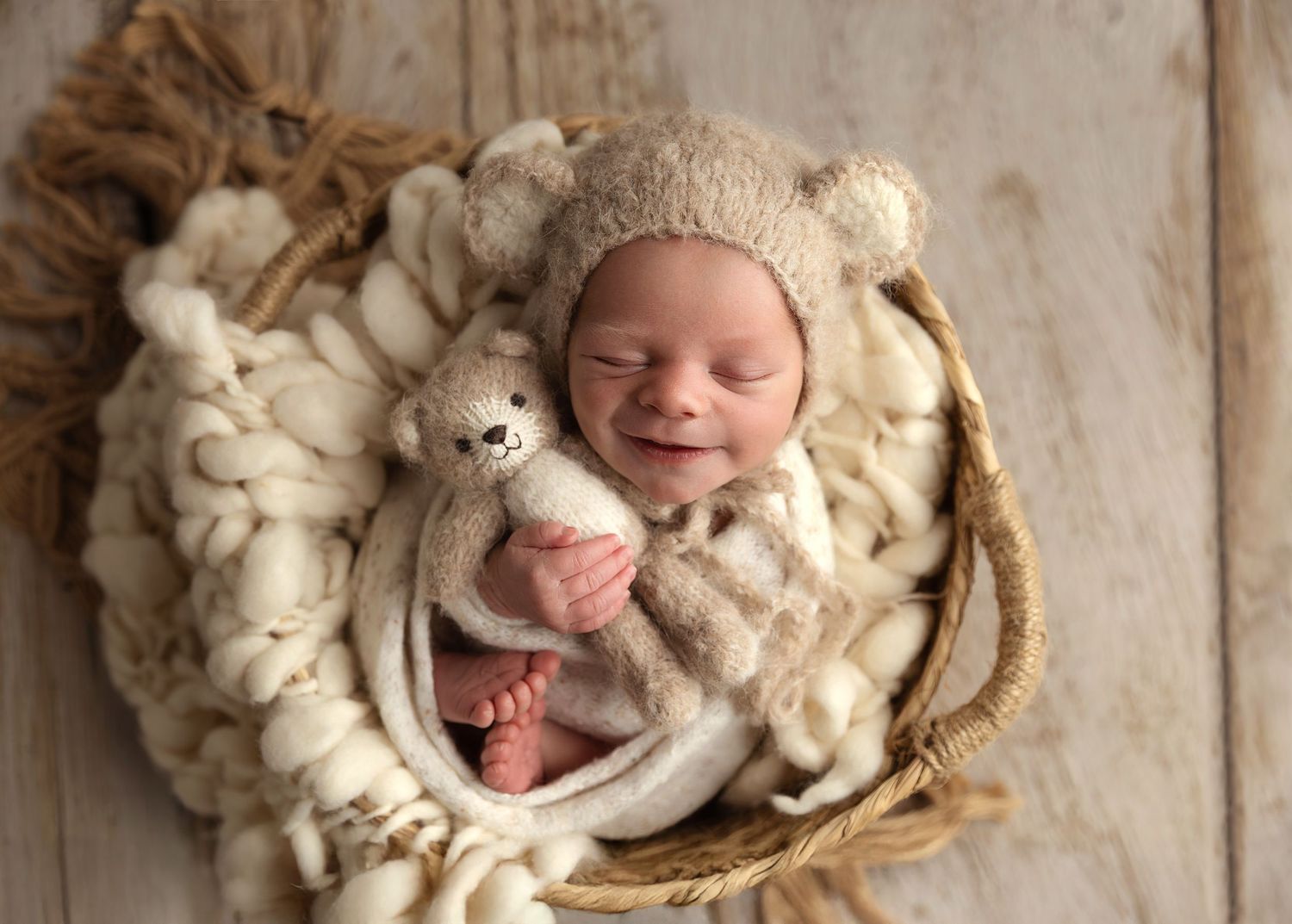 Image of Baby boy in a basket snuggling his teddy bear