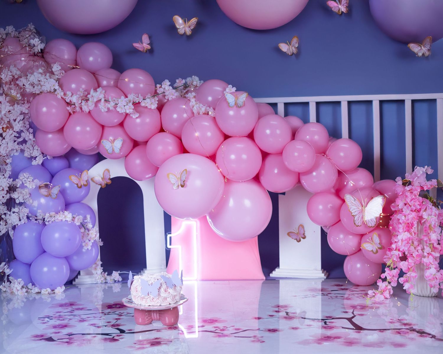 Pink and purple balloon arch with cherry blossoms and butterflies creating a dreamy party backdrop.