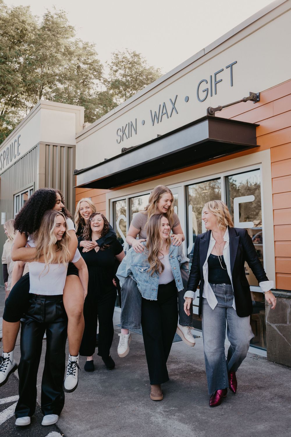 Group walking and laughing together outside a Skin Wax Gift storefront.