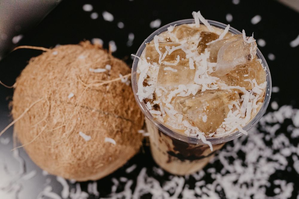 Close-up shot of coconut cocktail with shredded coconut garnish on dark background.