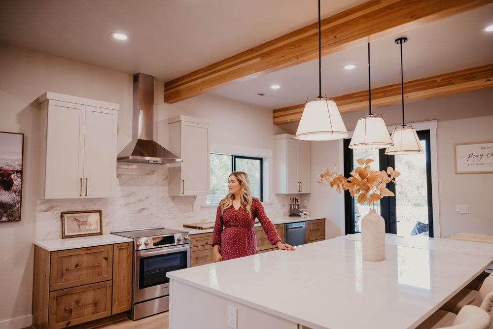 Modern white kitchen interior with wooden beams and pendant lights over island counter.