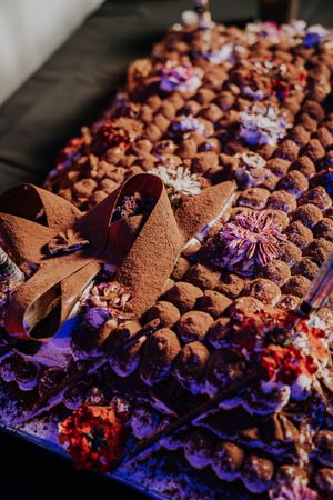 Luxurious display of chocolate truffles dusted with cocoa powder, garnished with colorful dried flowers.