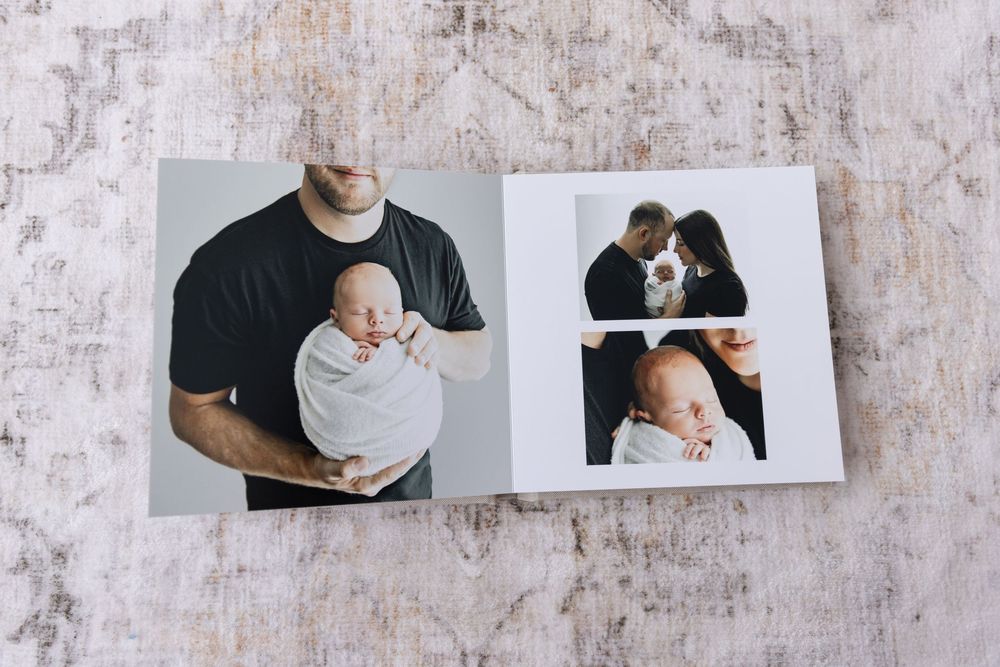 An open photo album showing a father holding a swaddled newborn with multiple portrait layouts.
