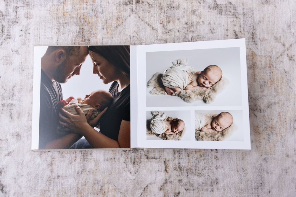 An open photo album displaying a family newborn session with multiple posed baby photographs.