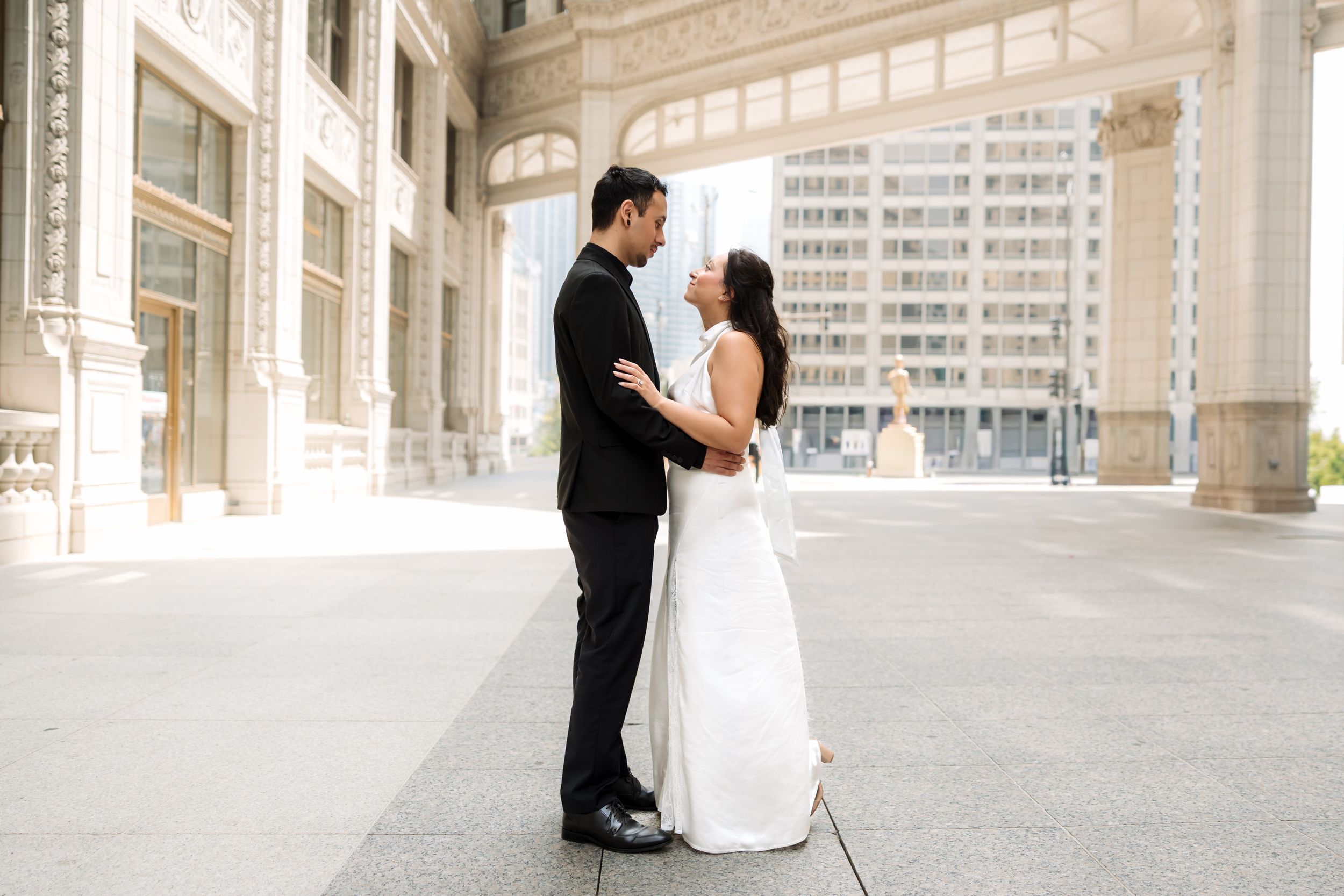 Bride and groom share a romantic moment outside a classic urban building on their wedding day.
