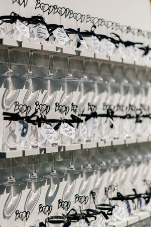 Elegant wedding escort card display with champagne flutes, black ribbon bows, and calligraphy name cards on tiered shelves.