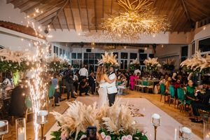 Couple shares first dance at elegant wedding reception with pampas grass, fairy lights, and gold chandelier.