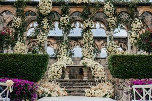 Elegant wedding ceremony altar adorned with lush white floral arrangements at a historic stone venue.