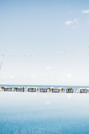Elegant outdoor wedding reception table setup overlooking a serene ocean under a clear blue sky.