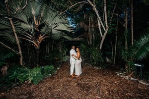 Couple embracing in a lush tropical forest setting at night surrounded by palm trees.
