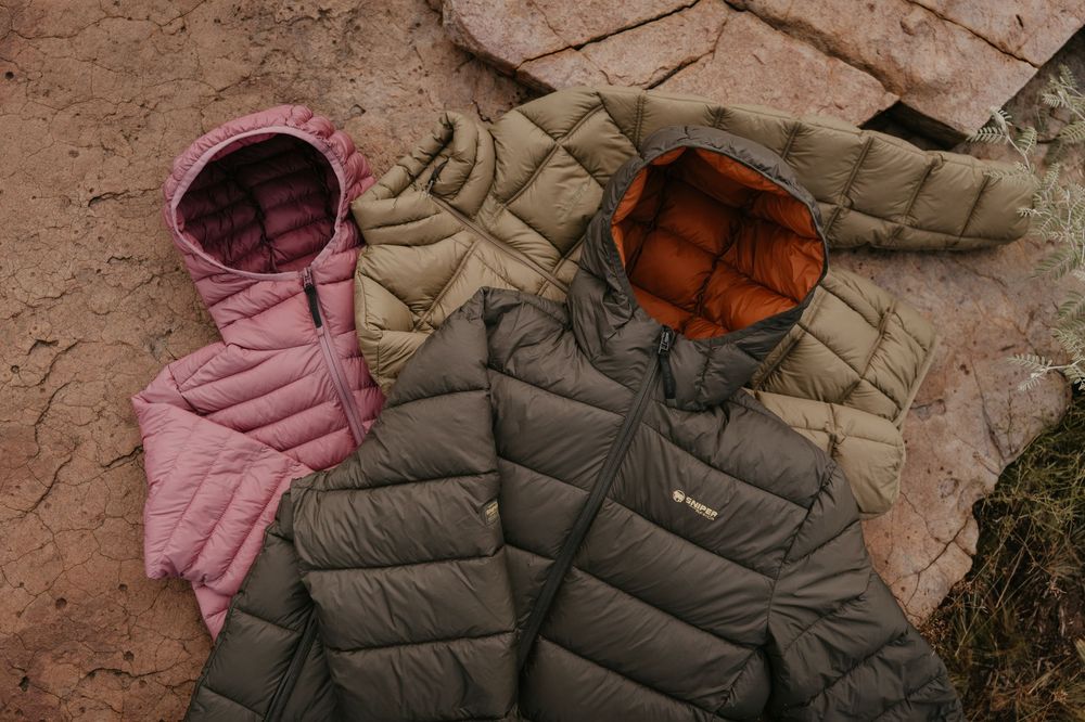 Pink and olive green hooded Sniper puffer jackets displayed on rocky terrain outdoors.