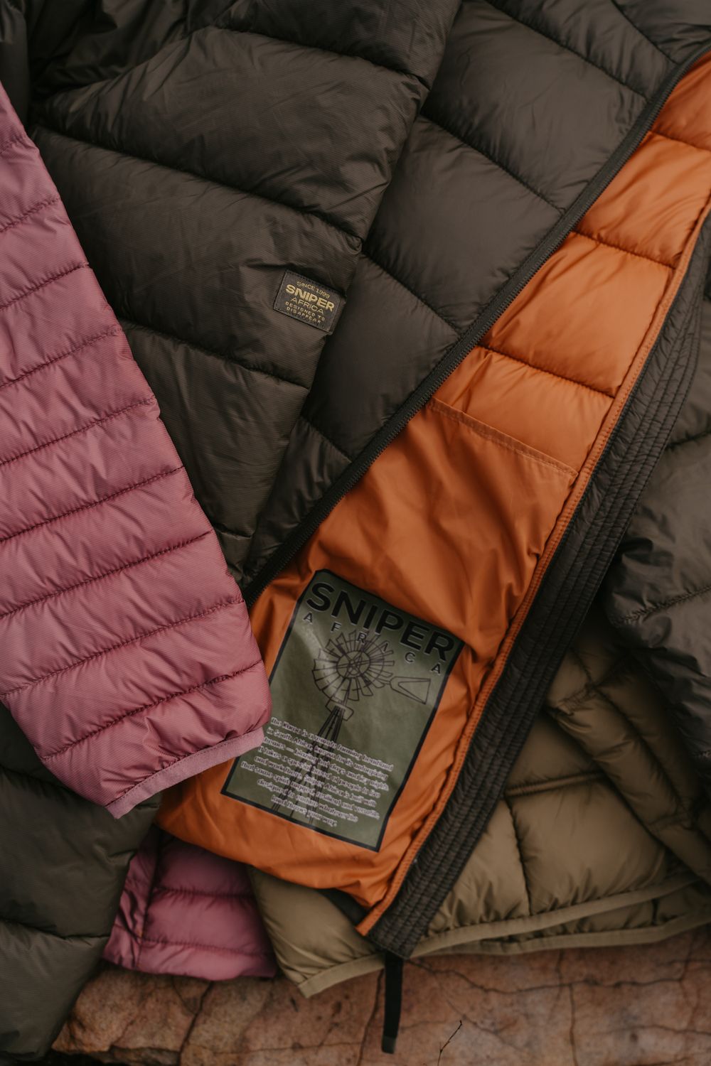 Collection of Sniper brand quilted puffer jackets in pink, olive, and orange colors laid flat.
