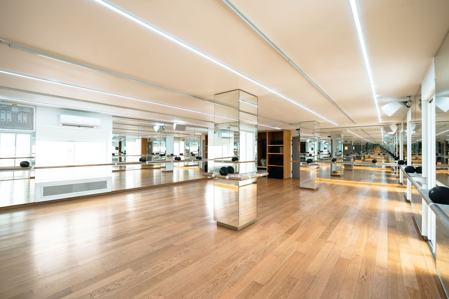 Darkened indoor cycling studio with rows of stationary bikes under geometric neon light patterns on ceiling.