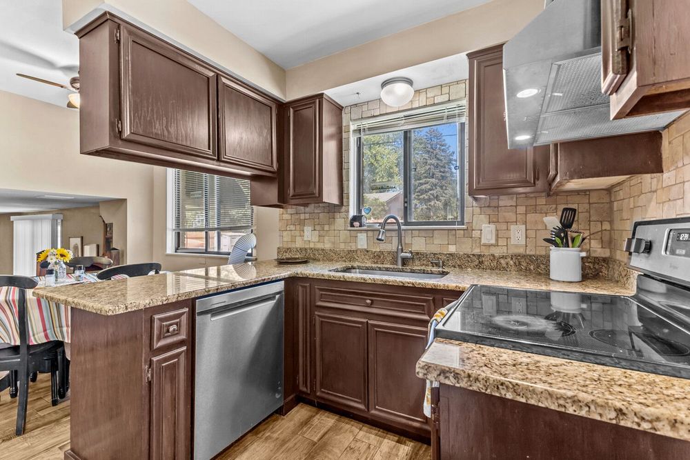 Kitchen with dark wood cabinets, granite countertops, stainless steel appliances, and stone tile backsplash.