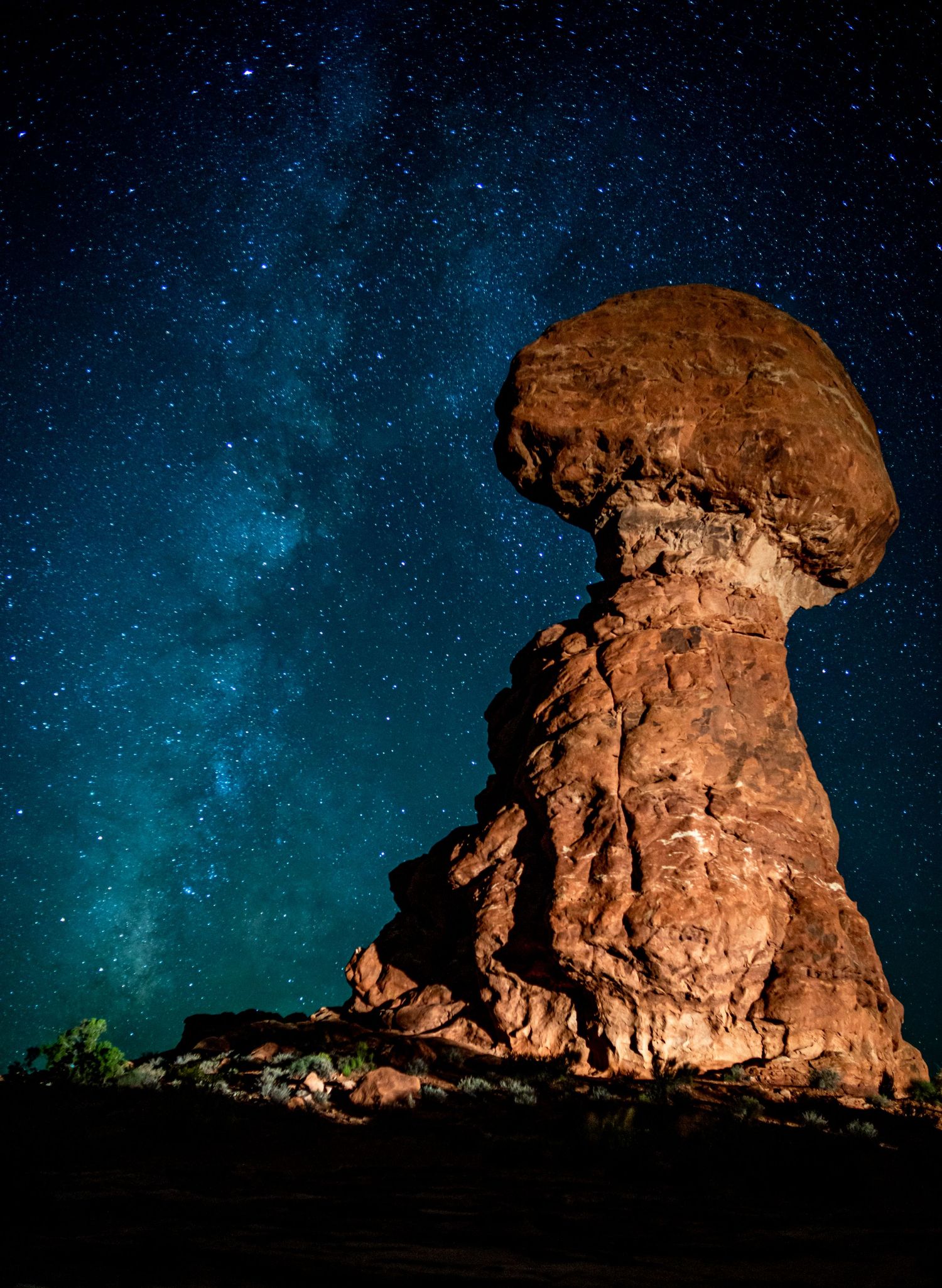 Balanced Rock formation silhouetted against a brilliant starry night sky with Milky Way at Arches National Park.