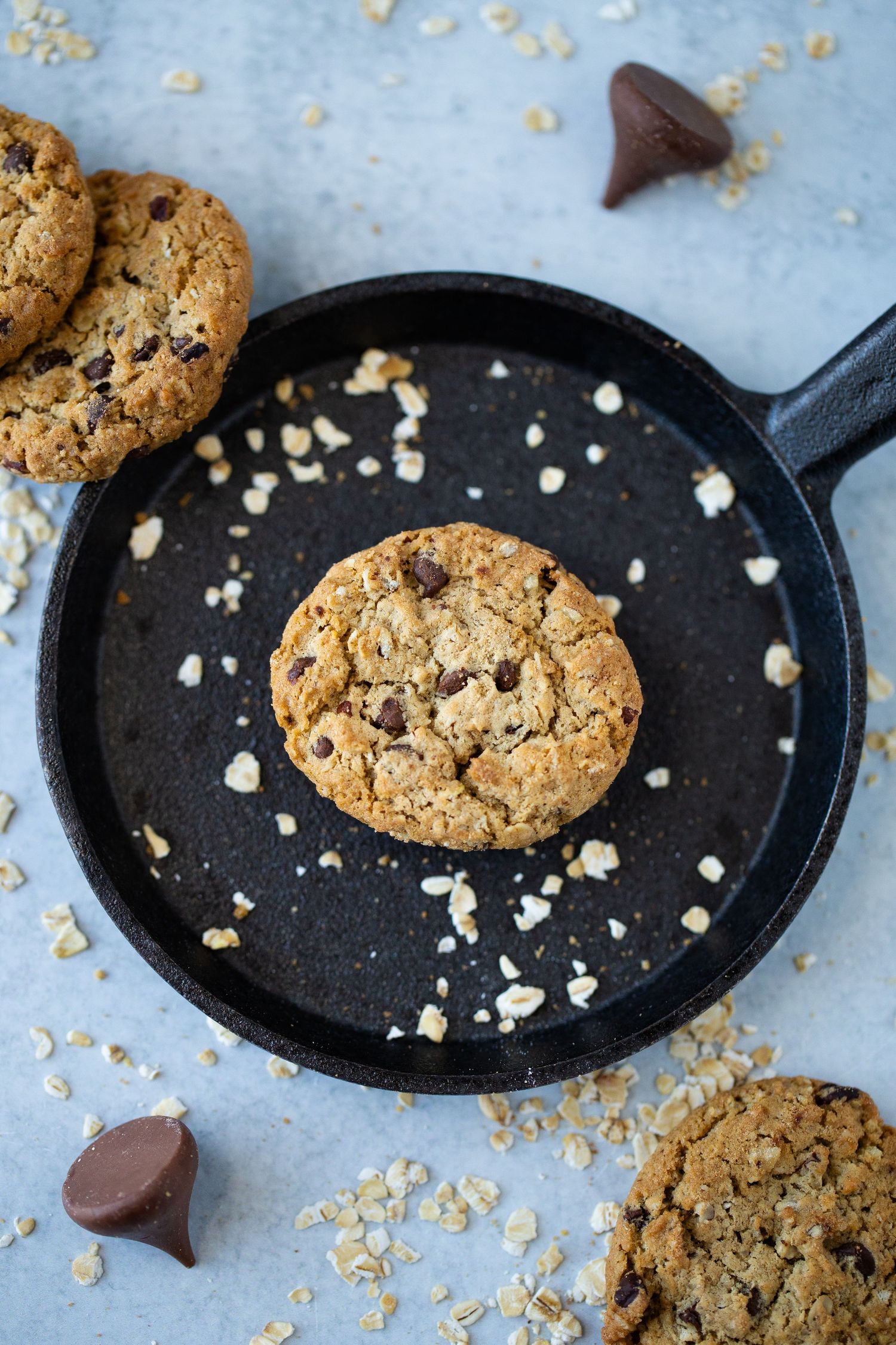 Overhead photo of a single Cowboy Cookie by HEB in a cast iron skillet with Hershey's kisses and oatmeal sprinkled around the frame.