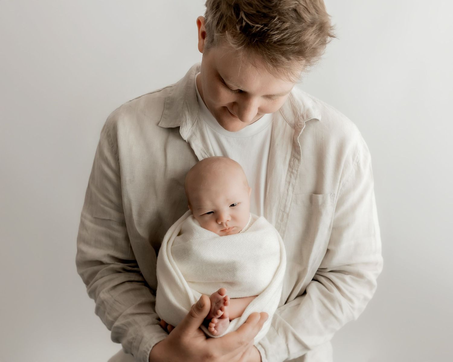 father cuddling newborn baby during portrait session