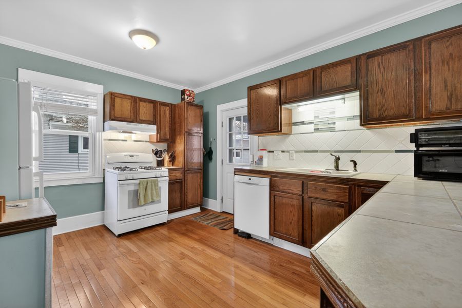 Traditional kitchen with dark wood cabinets, hardwood floors, white appliances, and green crown molding accents.