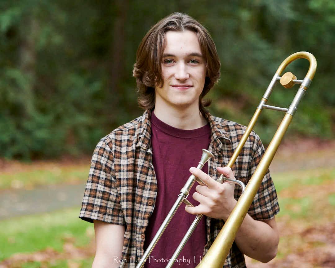 High school senior male standing at Snoqualmie-Preston trailhead with trombone