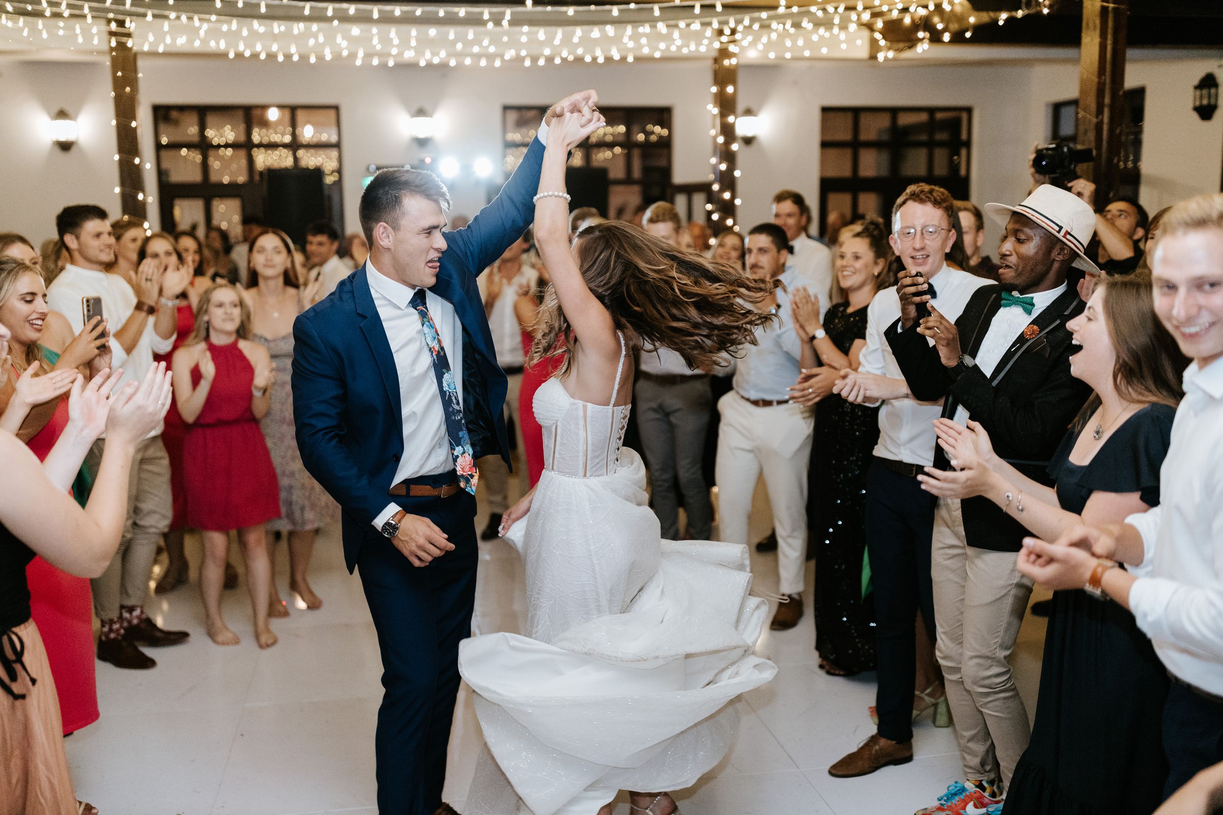 Newlyweds share a joyous dance moment surrounded by celebrating guests at their wedding reception.