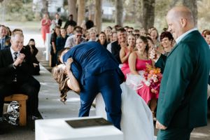 A playful wedding ceremony moment captured with guests watching and smiling.