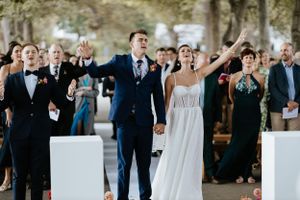 A joyful celebration during a wedding ceremony with guests cheering in the background.