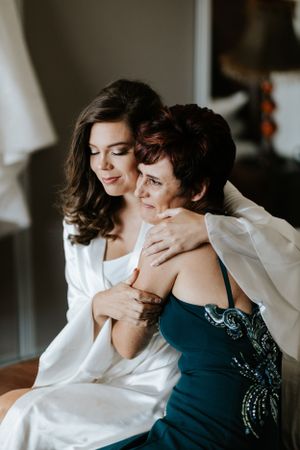 Emotional moment between two people in white robe and navy dress during wedding preparations.