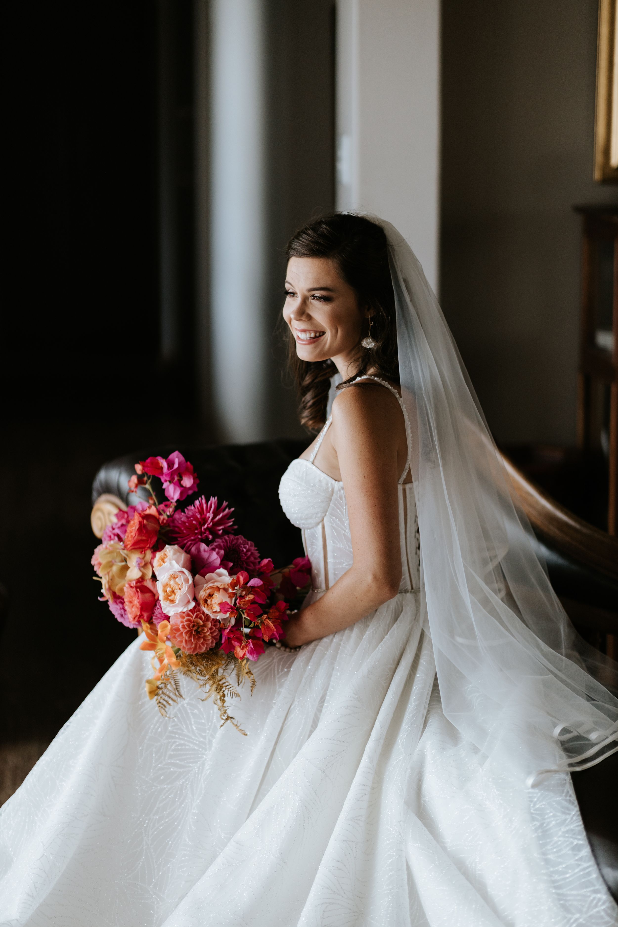 Bride in classic white ball gown holding vibrant pink and coral bouquet.