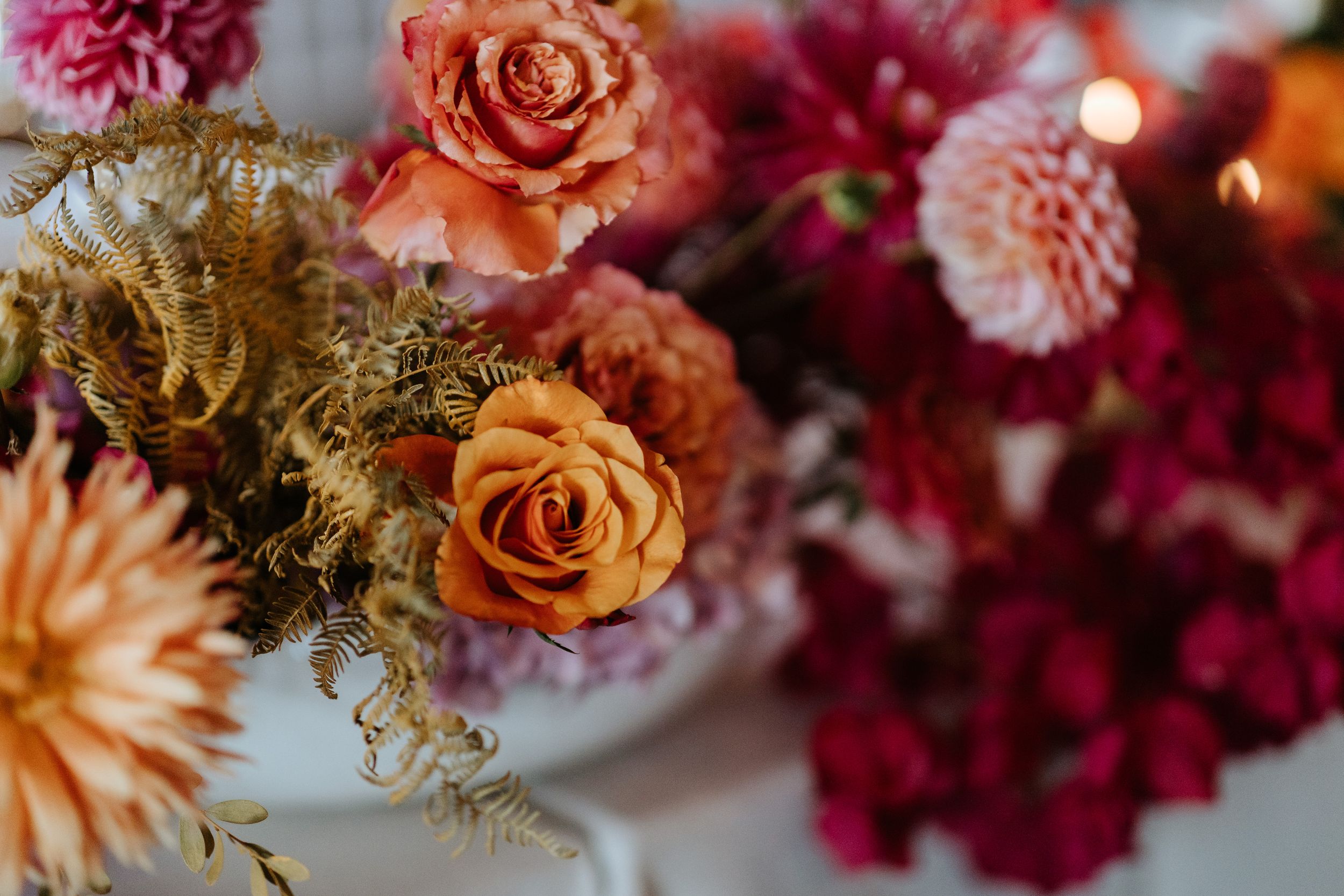 Beautiful floral arrangement featuring pink and orange roses with deep burgundy dahlias.