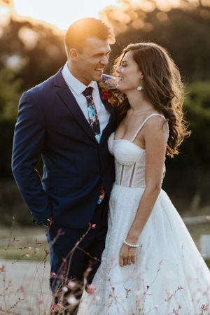 Intimate wedding portrait of couple in golden sunlight with florals.