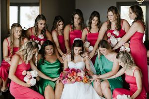 Wedding party wearing pink and green dresses gathered together on couch.