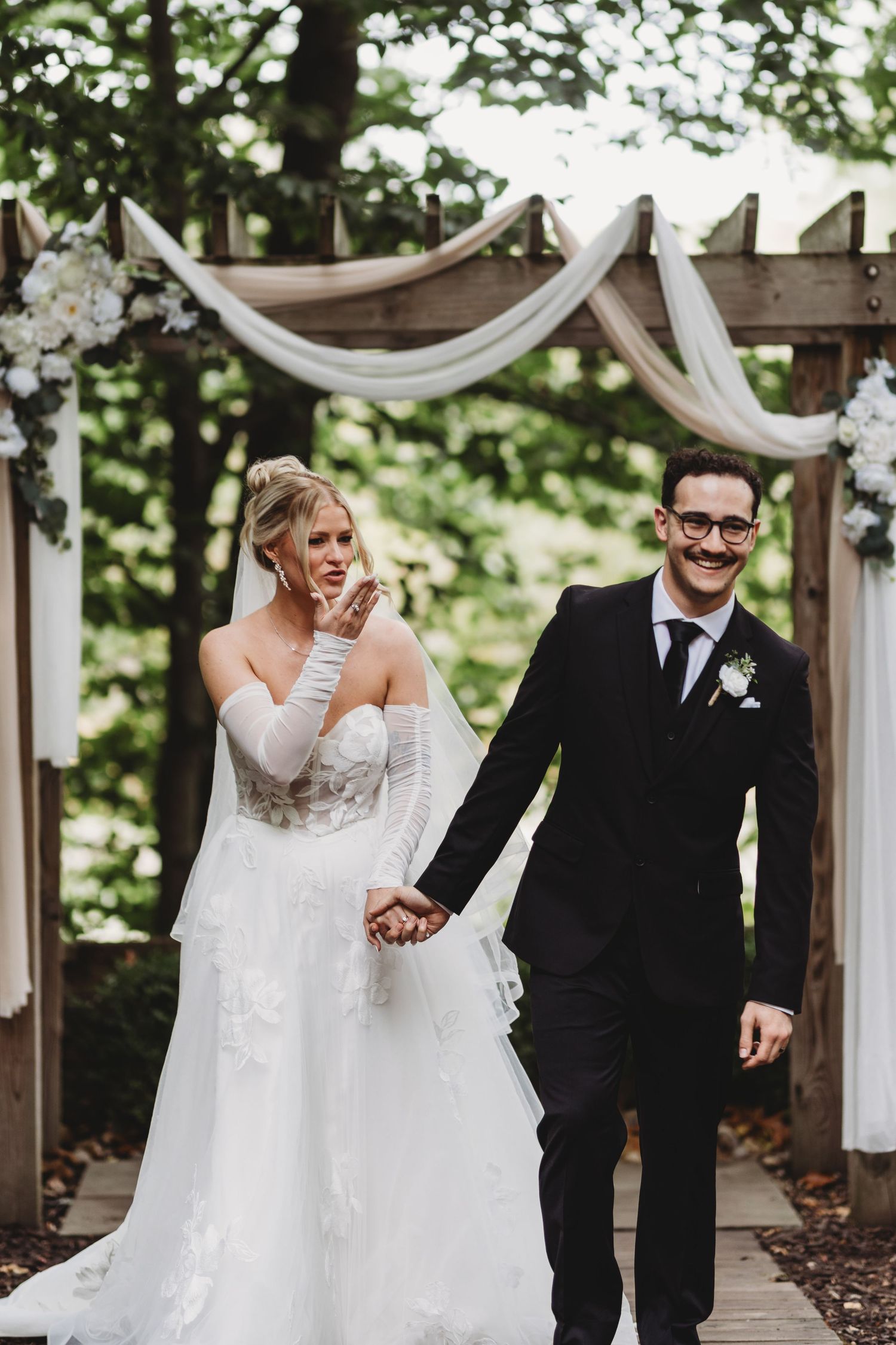 Black and white photo of bride and groom sharing an emotional first dance hug at elegant wedding reception.