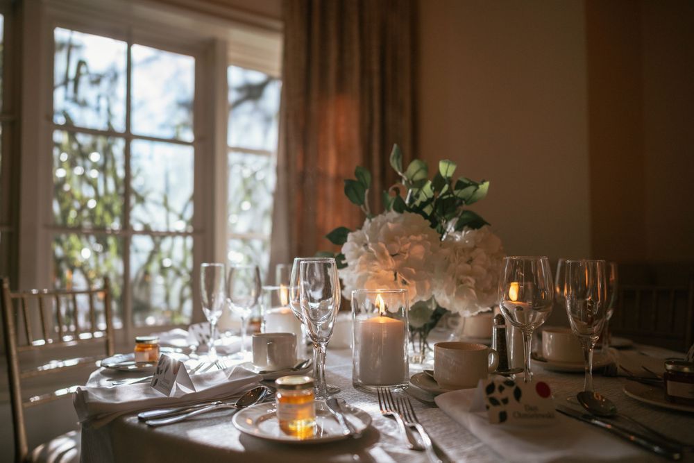 Elegant wedding table setting with white floral centerpiece, candles, and crystal glassware in warm natural light.