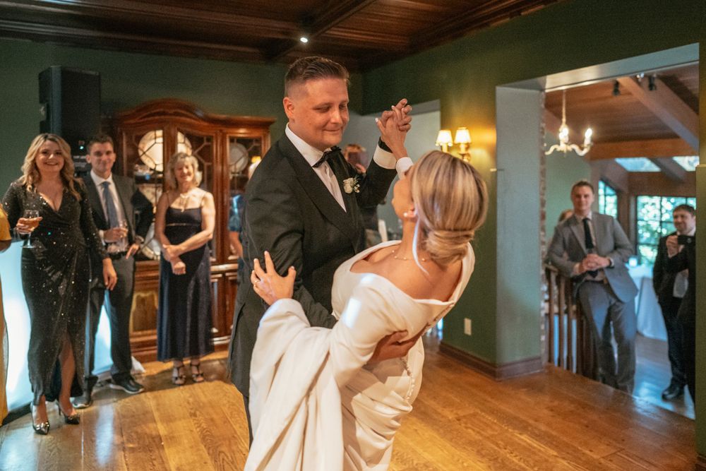 Bride and groom share first dance at wedding reception while guests watch and celebrate.