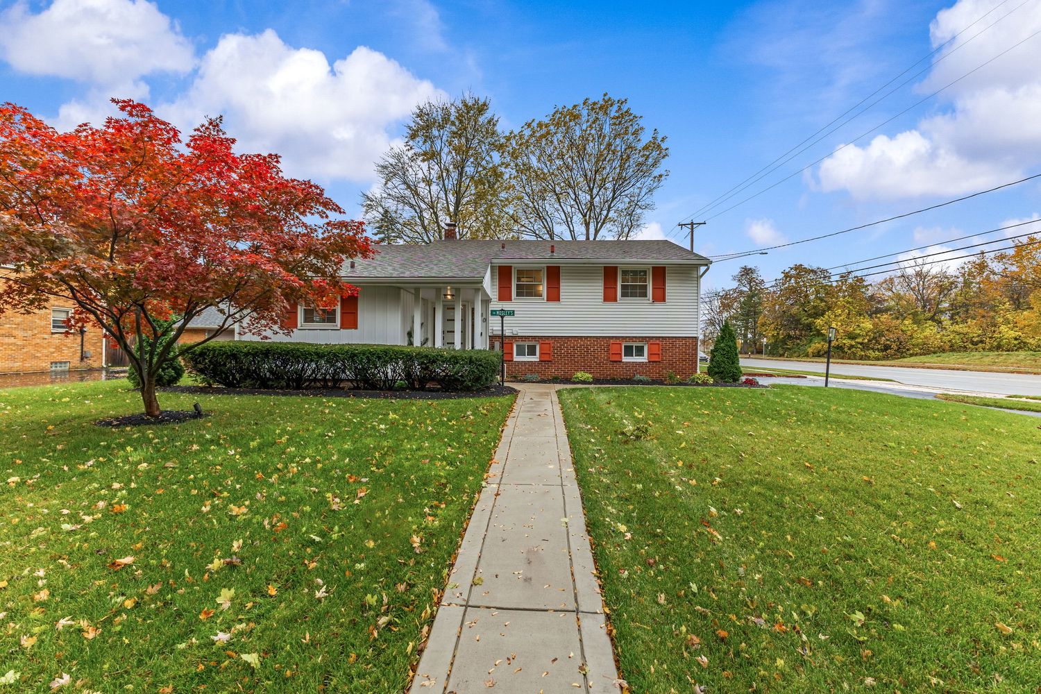 Charming white clapboard bungalow with covered front porch, brick garage, and small front yard.