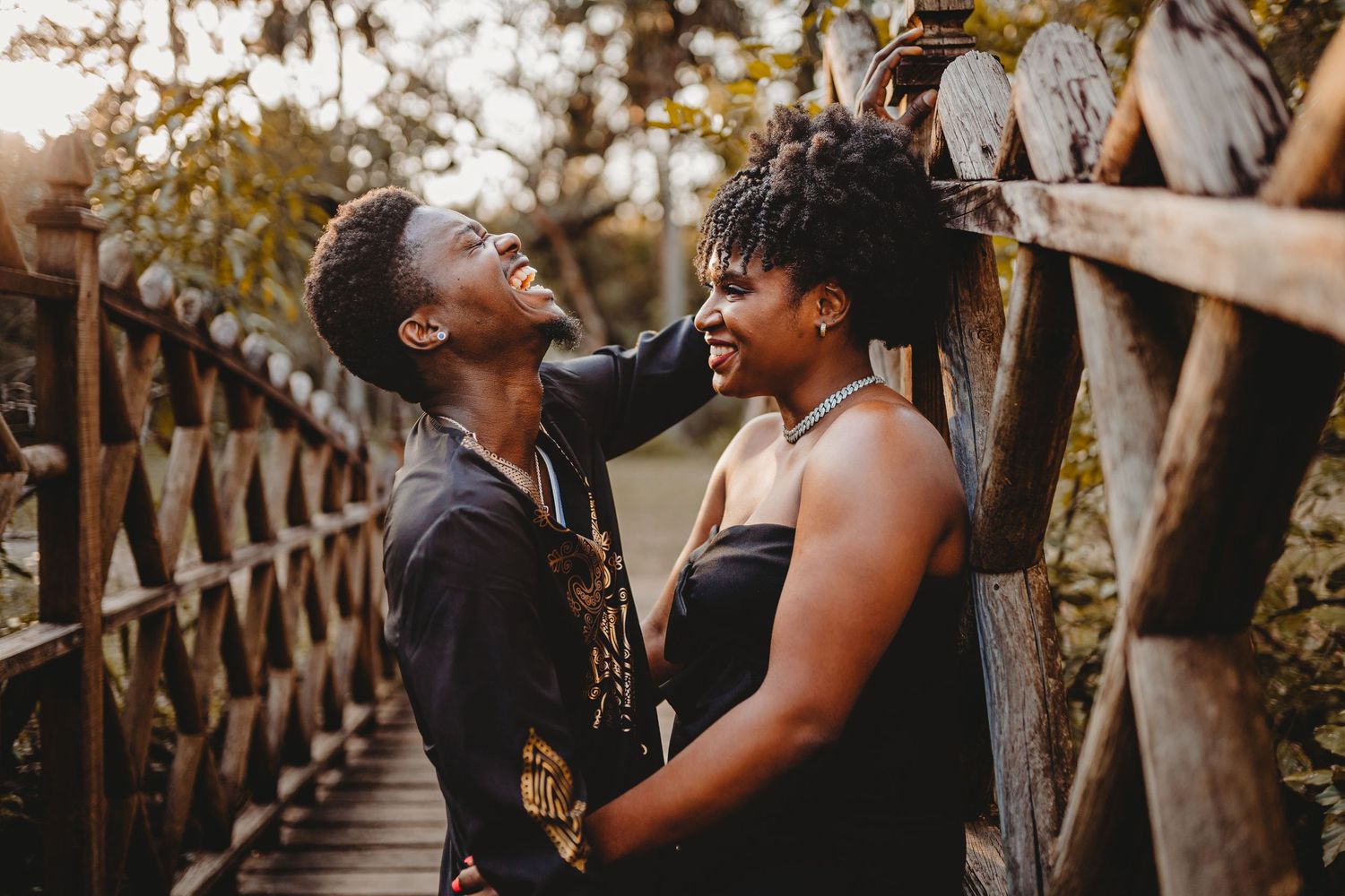 Two people sharing a joyful moment on a wooden bridge, smiling at each other in warm golden light.