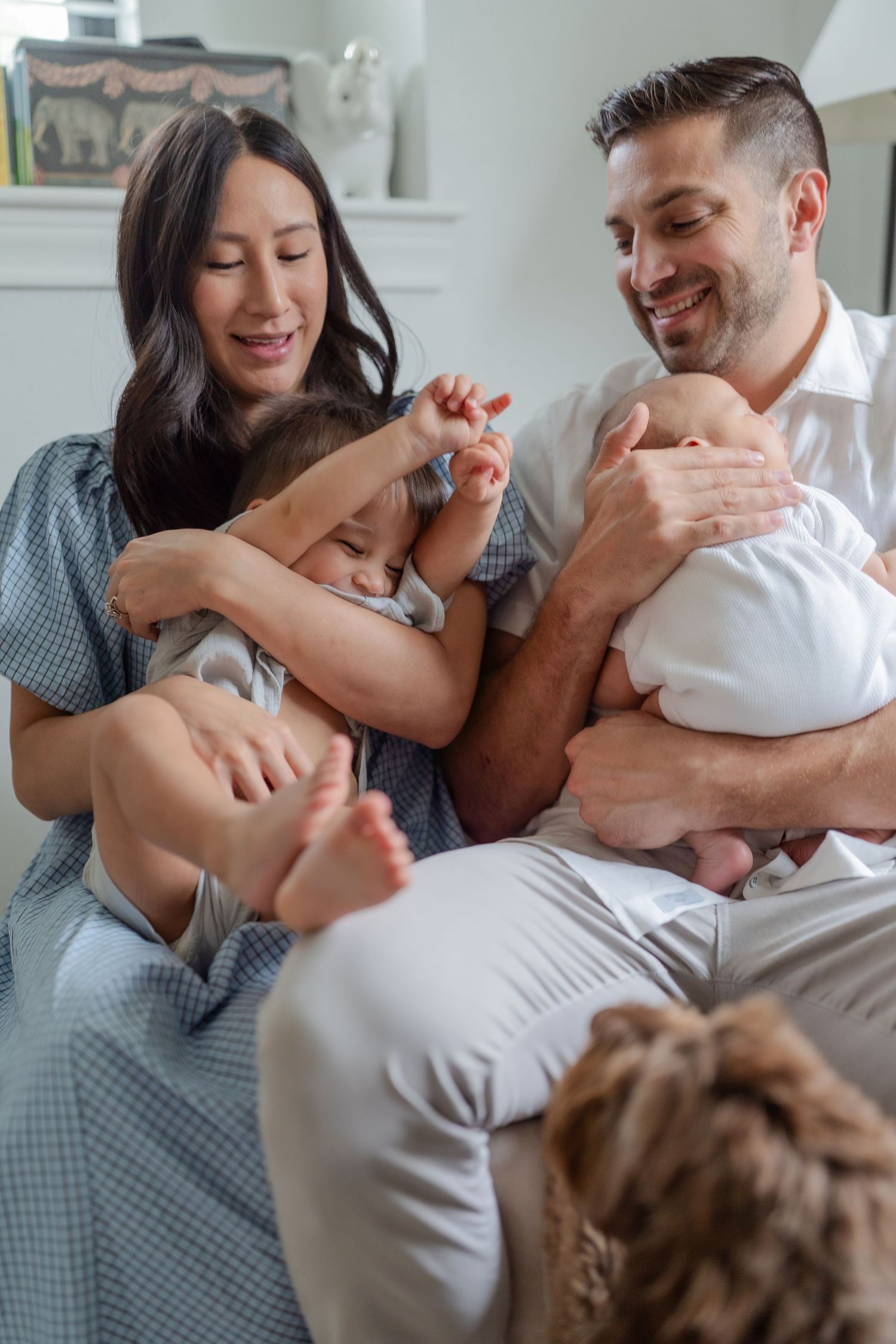 newborn family photo session in nursery mom tickling toddler mom wearing baby blue dress