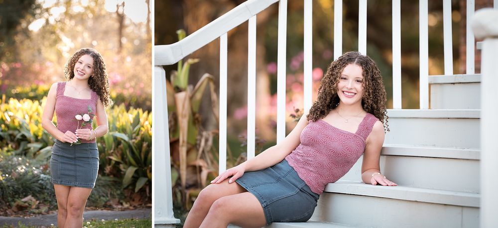 Young woman with curly hair posing in a pink top and gray skirt near garden stairs and colorful flowers.