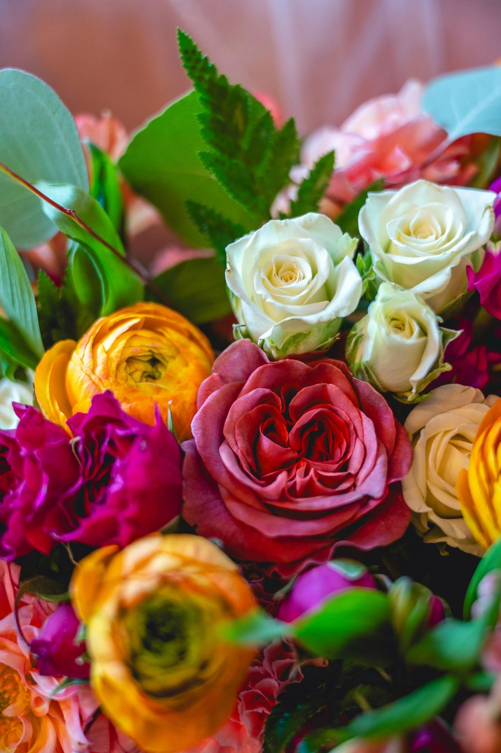 Vibrant bouquet of colorful flowers including red, white, yellow, and pink roses with lush green leaves.