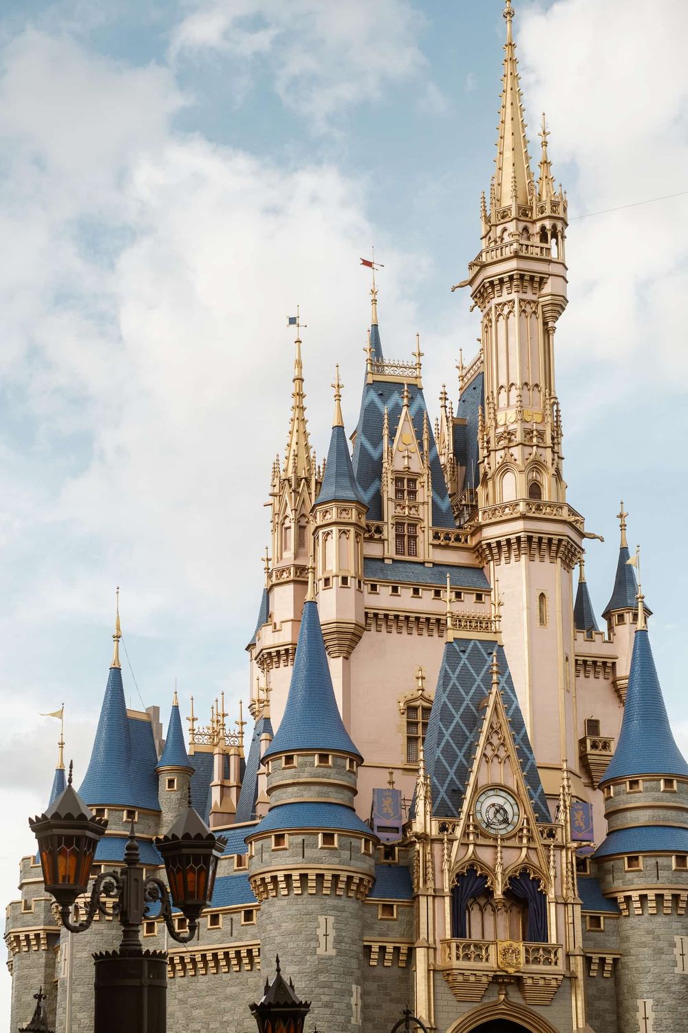 Cinderella Castle at Magic Kingdom, Walt Disney World, featuring blue spires and golden accents against a cloudy sky.