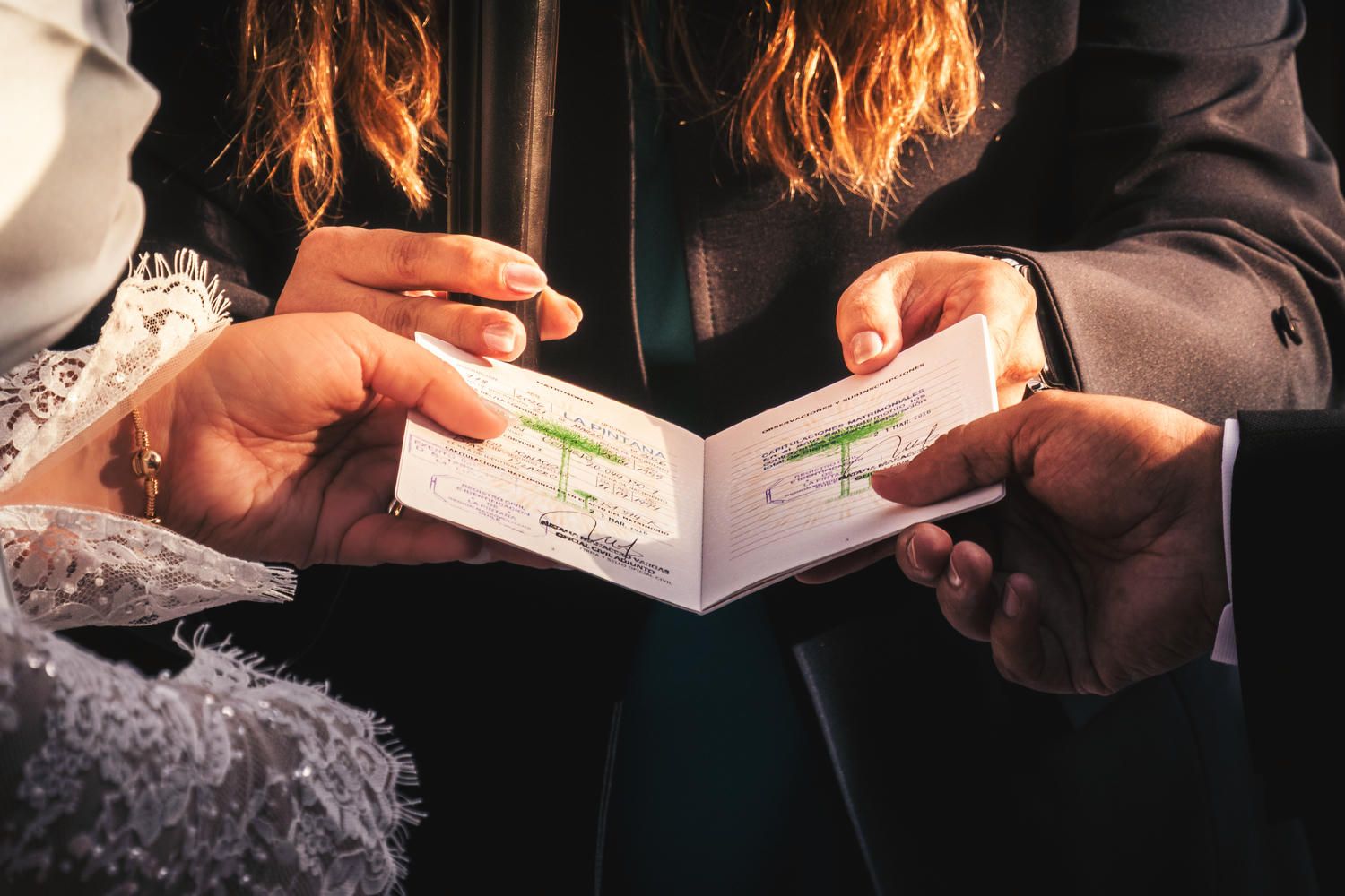 Couple exchanging wedding vows booklets during a marriage ceremony, close-up of hands holding documents.