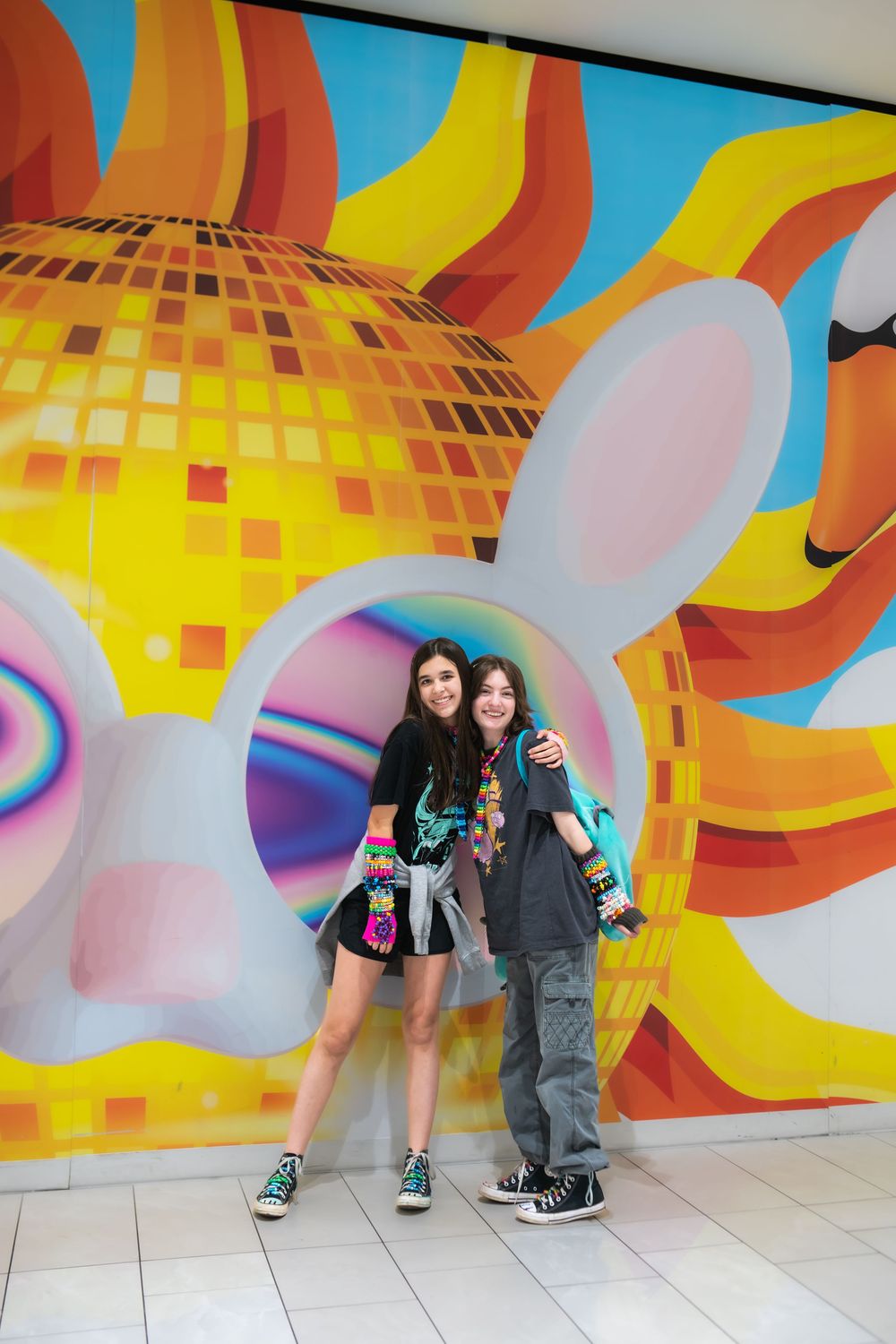 Two teens pose in front of a colorful bunny disco ball mural at a pop art installation.American deam Mall