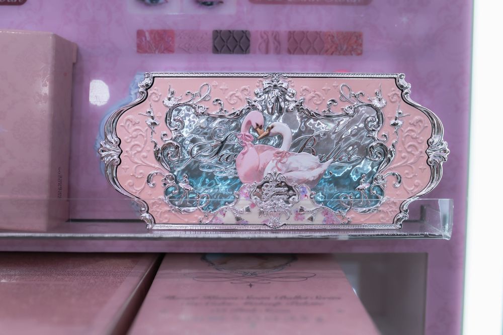 Pink decorative box featuring elegant silver-framed swan design with blue accents and ornate baroque styling.