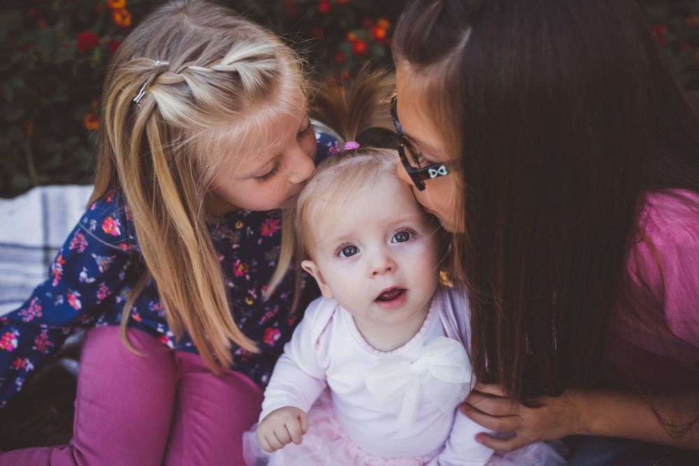 older siblings kissing little sister during family photos in the inland empire